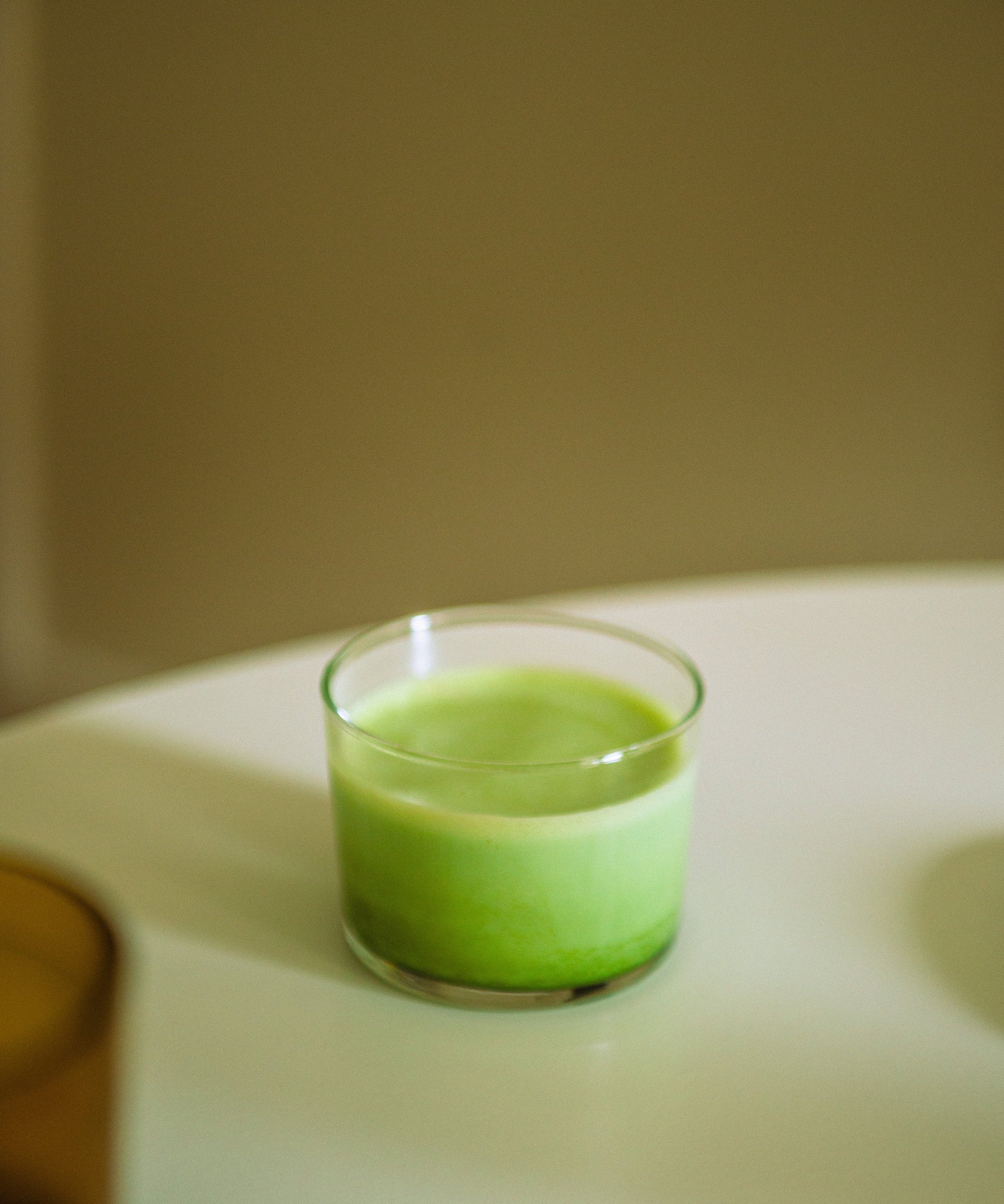 A matcha latte in a glass cup in front of a thea premium matcha pouch