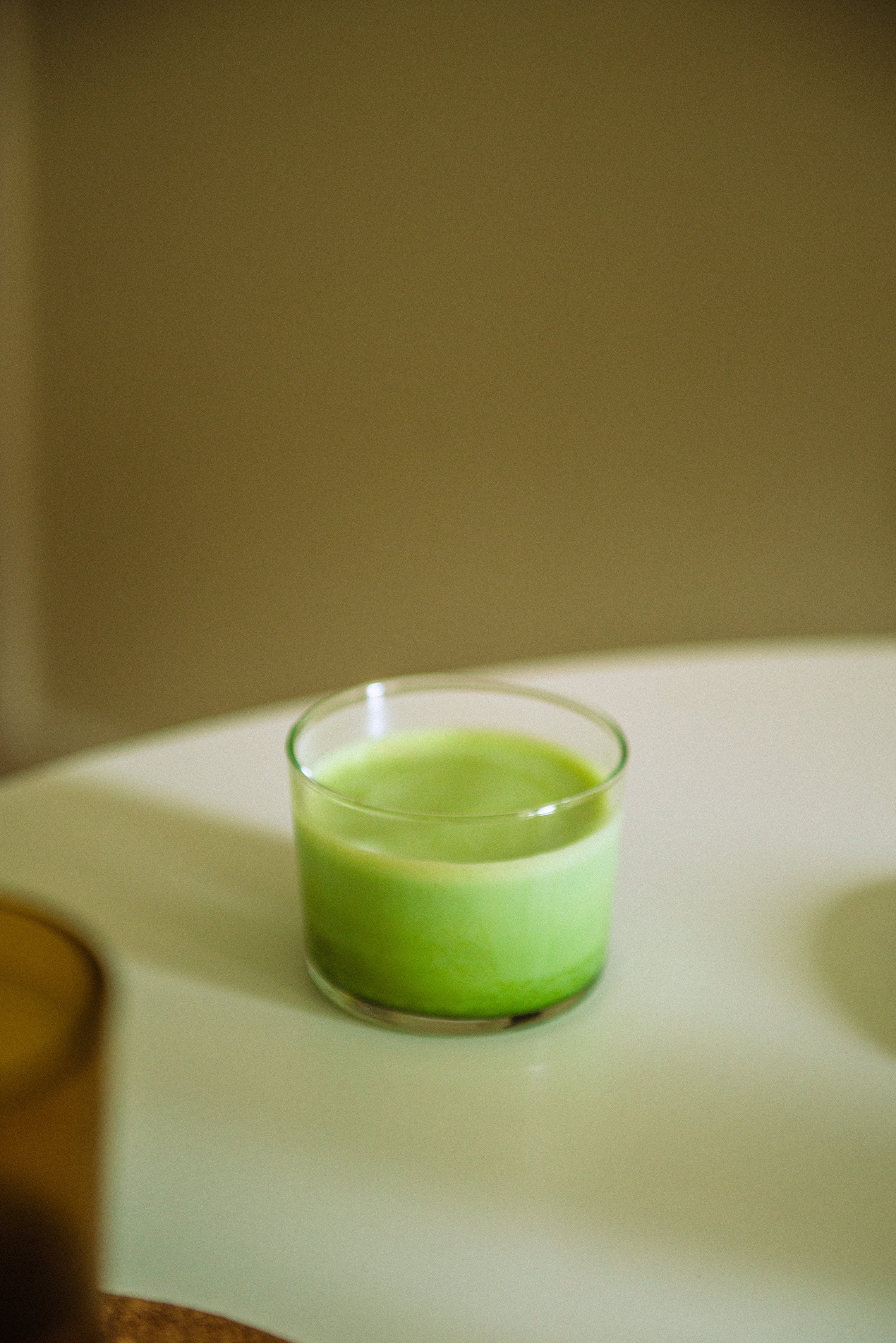 A matcha latte in a glass cup in front of a thea premium matcha pouch