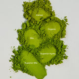 Five different grades of green matcha powder stacked vertically on a light gray background, labeled with white text as Kansai, Organic, Mie, Superior Kyoto, and Superior Mie.