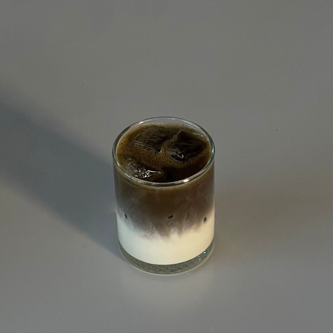 Glass with layered drink on a gray background